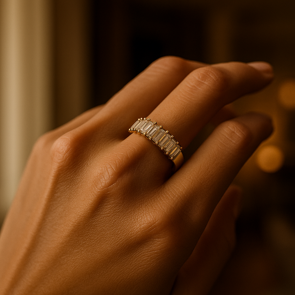 Hand wearing a gold ring with gemstones against a blurred background
